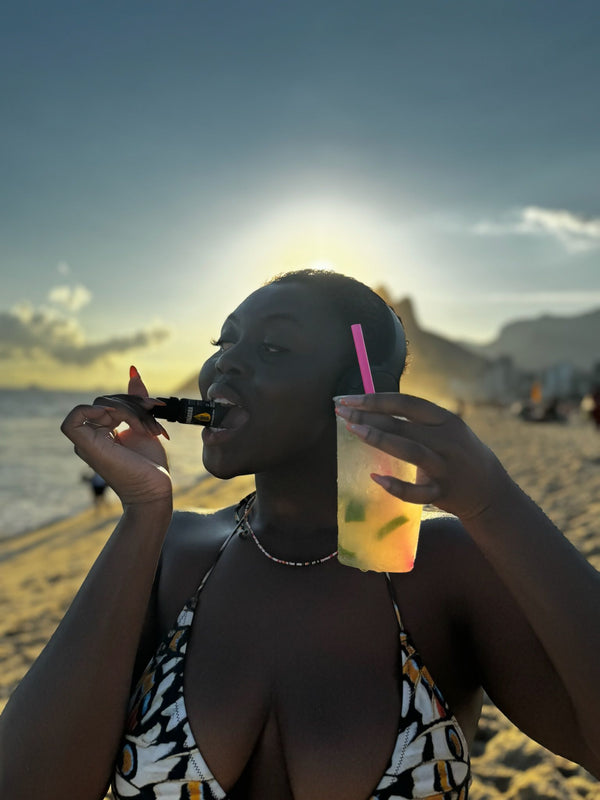 Woman enjoying a drink with a straw on a beach at sunset