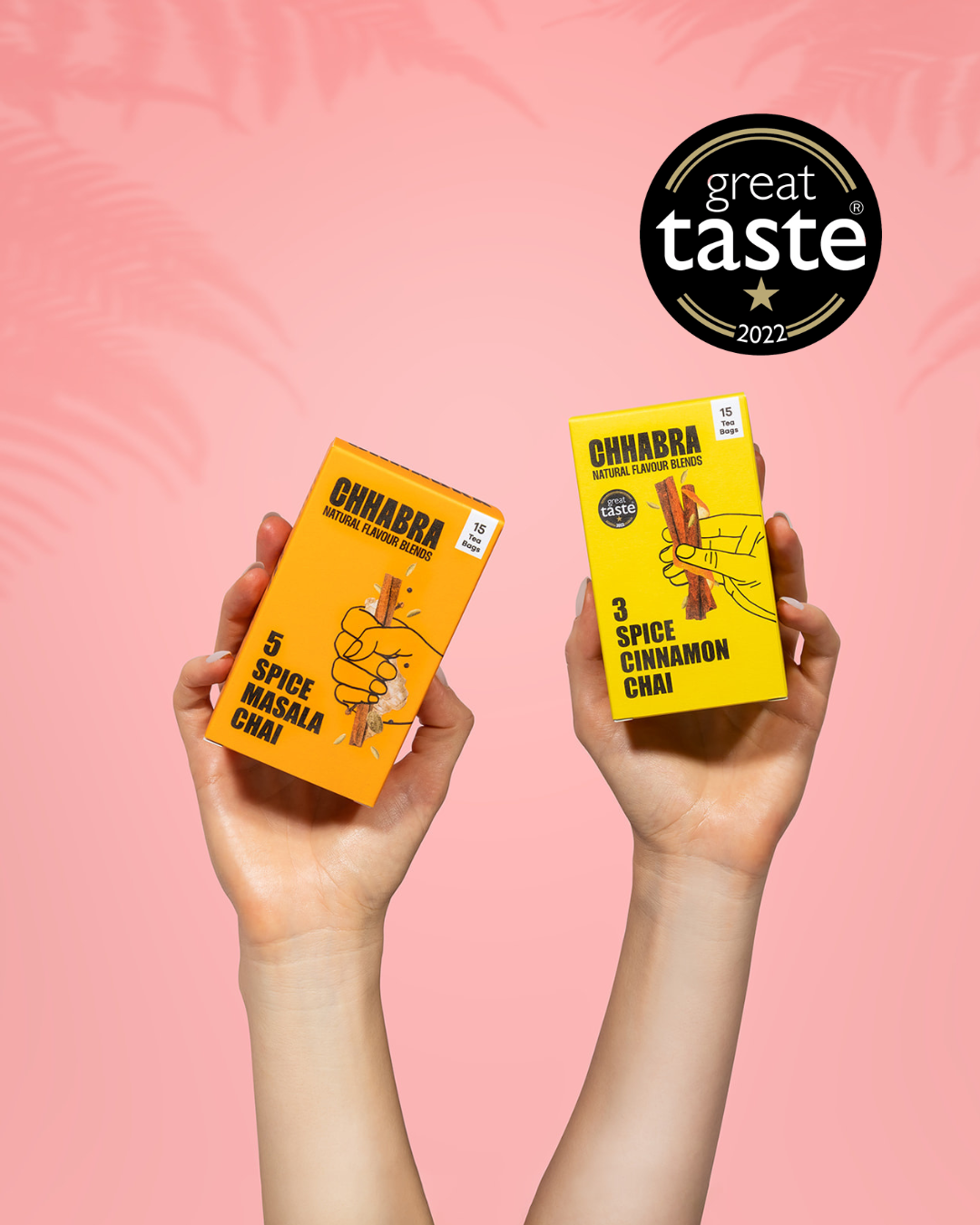 Two hands holding Chhabra tea packages with a 'Great Taste' award on a pink background